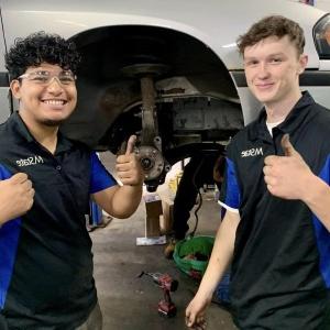 Fix It Forward volunteers give the thumbs up next to a car they fixed up for someone in need